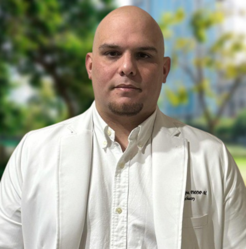 Jonathan D. Tapia, PMHNP-BC – Mental Health Specialist at Regions Praxis Care Corp Portrait of Jonathan D. Tapia, PMHNP-BC, psychiatric mental health nurse practitioner at Regions Praxis Care Corp, wearing a white coat, standing against a blurred outdoor background.